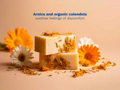 Mustela USA |Two bars of soap with calendula petals and flowers on a beige surface.