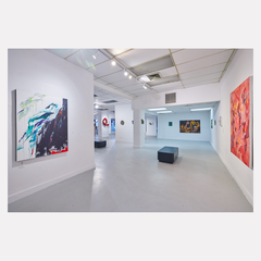 The artwork 'Kaaterskill Falls' by W Lu is displayed in a modern gallery space featuring white walls and track lighting. The abstract painting combines vibrant turquoise and blue tones with dynamic brushstrokes, suggesting a mountainous landscape. The 50x35 inch acrylic canvas hangs alongside other contemporary artworks in the bright, minimalist exhibition space.