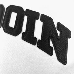 Closeup of black textured letters OIN on a white fabric background