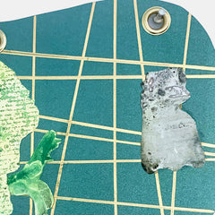 The artwork 'I Am Talking, Cat' features a geometric grid pattern on metallic teal paper with intersecting gold lines. Two silhouetted figures, one in textured green with handwritten text and another in mottled gray, appear against the gridded background. Metal grommets accent the corners. Mixed media collage by Sunny Chapman.