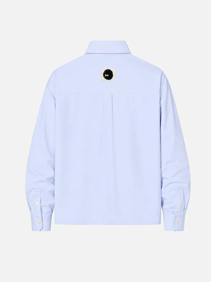 shopi go Meguro Regular Shirt – açık mavi, arka görünüm, küçük siyah daire logolu etiket