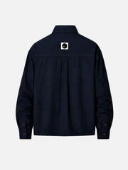 shopi go Meguro Regular Shirt – Navy, arka görünümde orta üstte beyaz kare rozet ve siyah daire