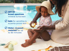 Mustela USA | Mother applying Mustela SPF 50 mineral sunscreen on her toddler's legs by a pool. Key benefits: broad-spectrum SPF 50, safe for sensitive and eczema-prone skin, water- and sweat-resistant up to 80 minutes.